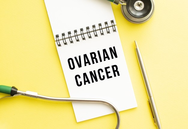 Ovarian cancer written in a notebook on a color table next to pen and a stethoscope